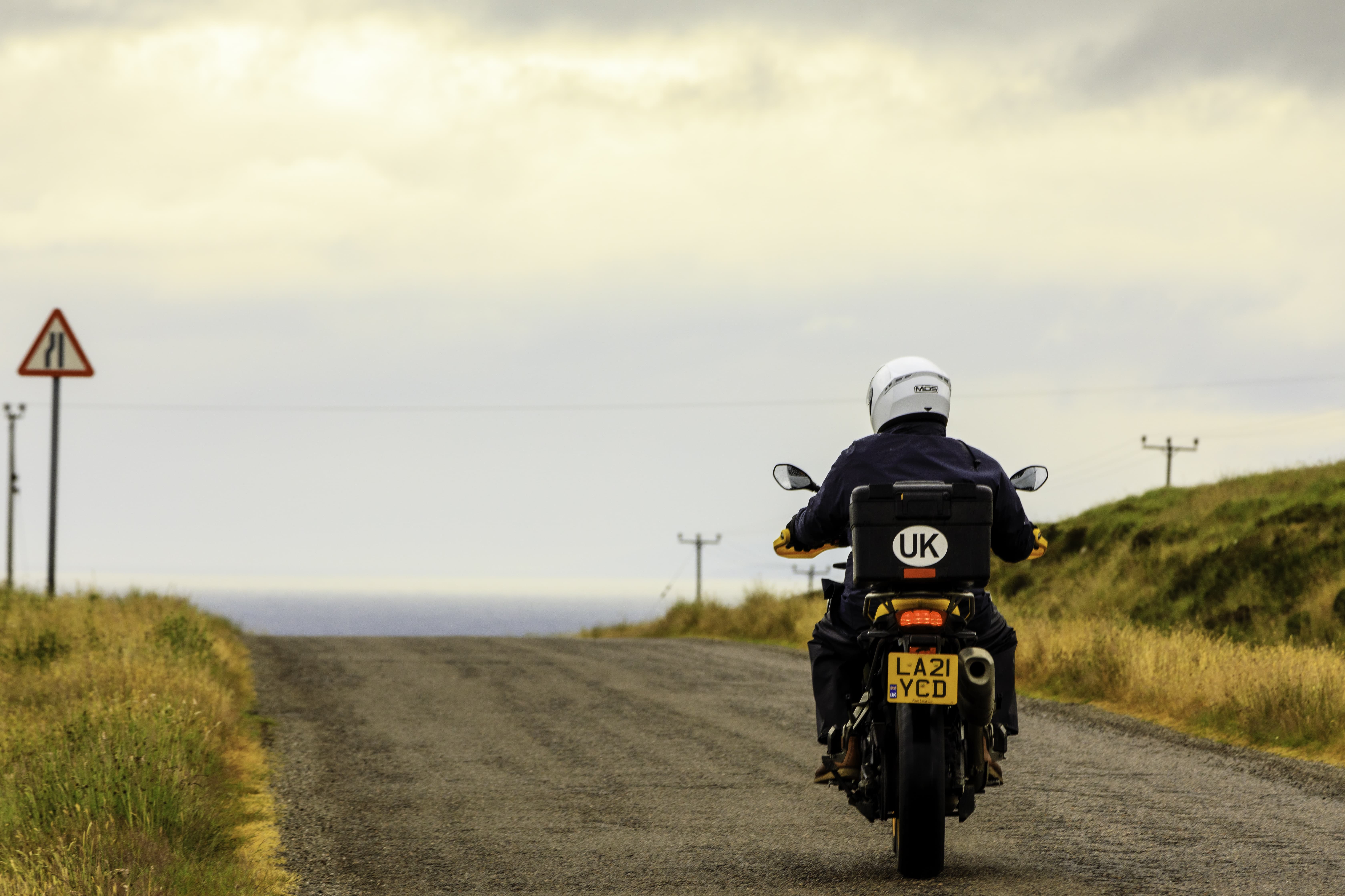 A motorcyclist ventures through the winding roads of the Scottish Highlands, embracing the freedom and solitude of the open landscape.