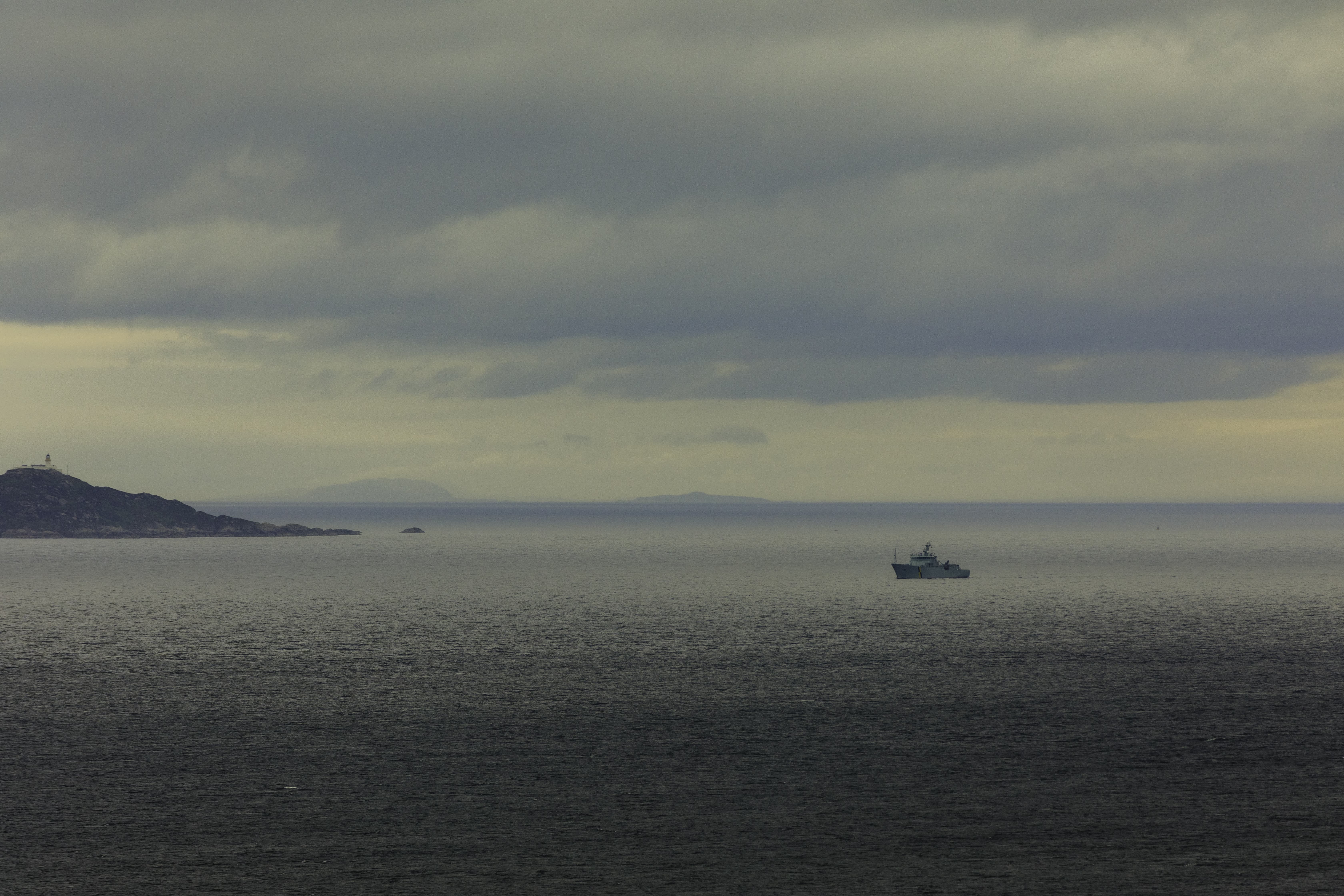 A solitary ship navigates the expansive waters off the coast of Scotland, standing as a silent sentinel against the vast horizon.